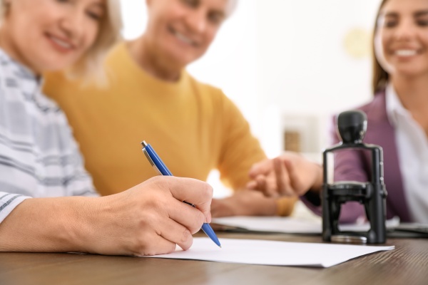 Mature couple signing document in notary's office, closeup
